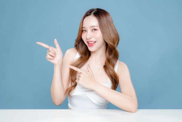 横を指さす女性